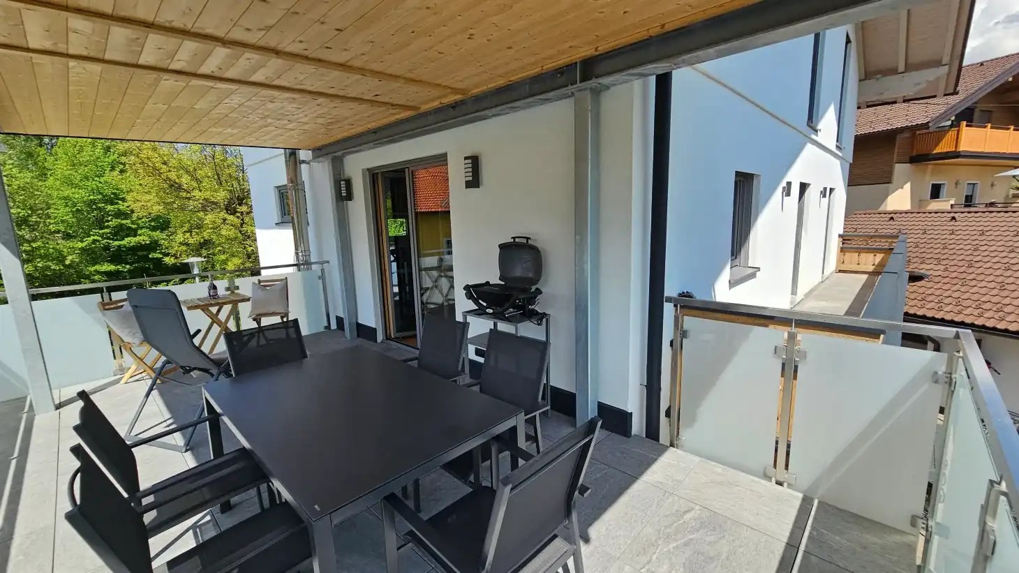 Überdachter Balkon mit Esstisch, Stühlen und Grill